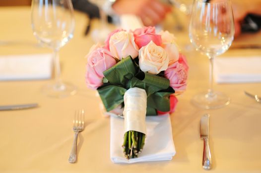 bridal bouquet on the table and two glasses on the background