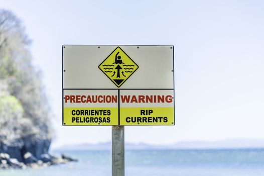 Warning sign for rip currents near an ocean beach.