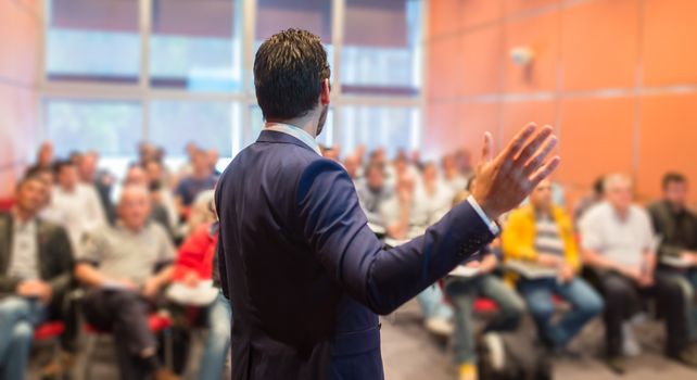 Speaker at Business Conference with Public Presentations. Audience at the conference hall. Entrepreneurship club. Rear view. Horisontal composition. Background blur.