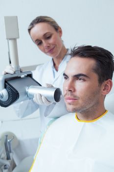 Serious young man undergoing dental checkup in the dentists chair