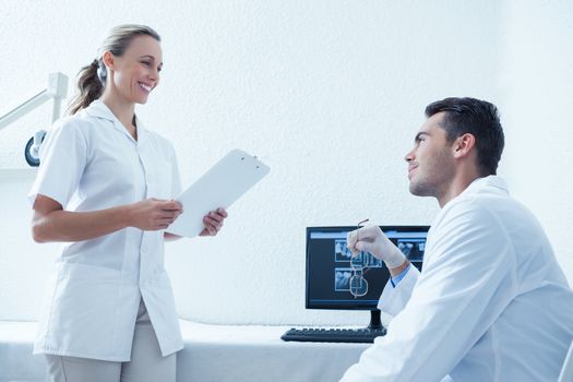 Side view of male and female dentists discussing reports