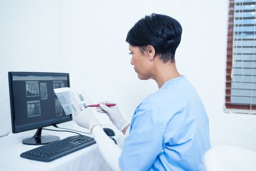 Concentrated female dentist looking at x-ray by computer