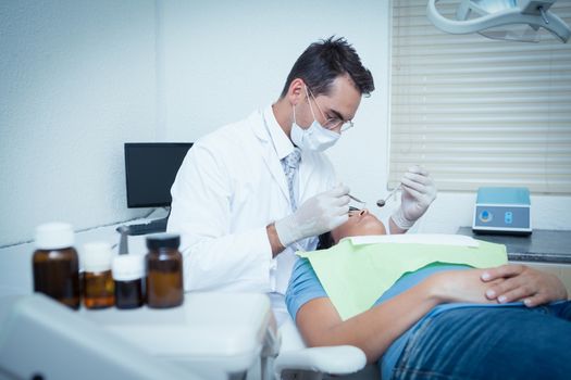 Male dentist examining womans teeth in the dentists chair