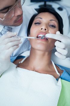 Male dentist examining womans teeth in the dentists chair