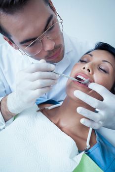 Male dentist examining womans teeth in the dentists chair