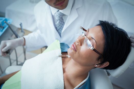 Male dentist examining womans teeth in the dentists chair