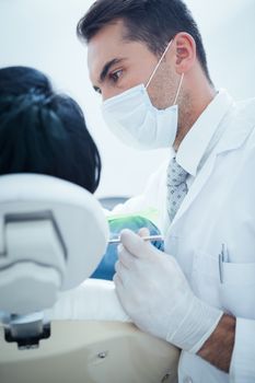 Male dentist examining womans teeth in the dentists chair