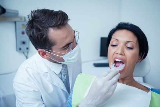 Male dentist examining womans teeth in the dentists chair