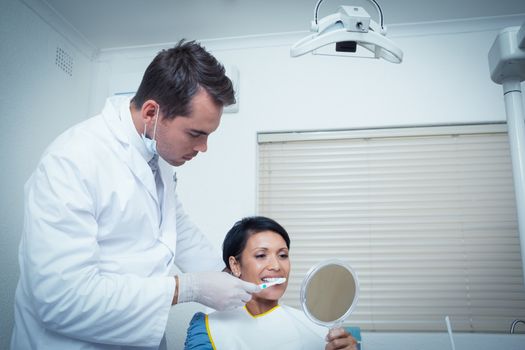 Male dentist brushing womans teeth in the dentists chair