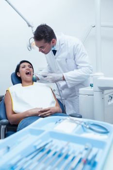 Male dentist examining womans teeth in the dentists chair