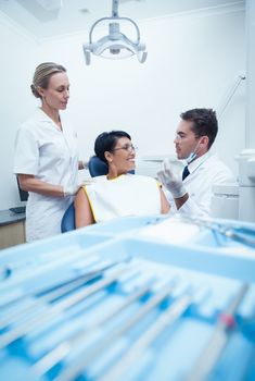 Female dentist with assistant showing woman prosthesis teeth