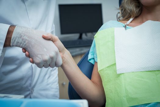 Close up mid section of male dentist shaking hands with woman
