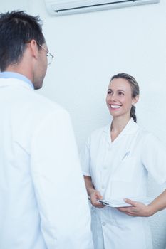 Smiling female and male dentists discussing reports