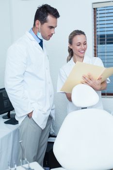 Smiling female and male dentists discussing reports