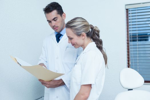 Side view of female and male dentists discussing reports