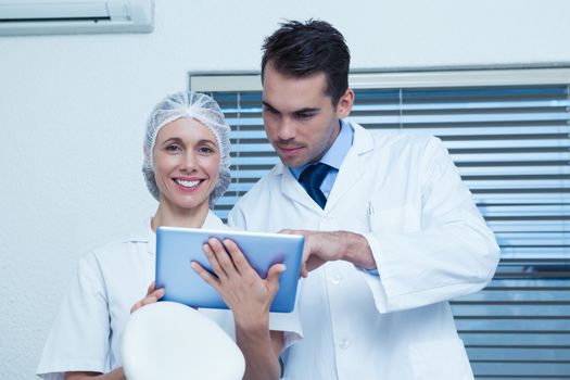 Male and female dentists using digital tablet