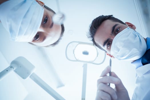 Low angle view of dentists in surgical masks holding dental tools