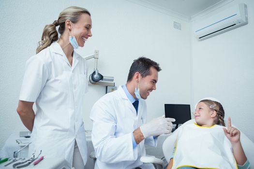 Male dentist  and assistant talking to girl in the dentists chair