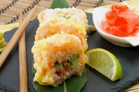 Hot Tempura Roll with Salmon and Avocado Served with Lime and Ginger closeup on Black Plate