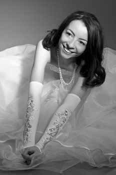 Black-and-White Portrait of Beautiful Bride Sitting on Floor over her Dress closeup