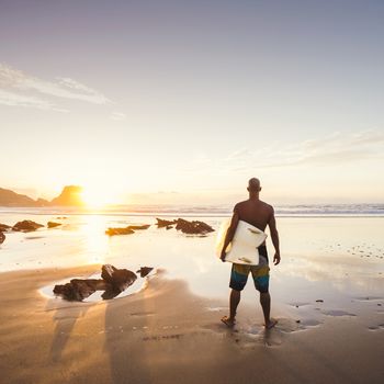 Silhouette of a surfer man at the beach with his surfboard