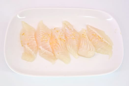 Fresh Dolly fish slice on white dish isolate on white background ready to be grilled.