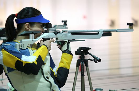 beautiful young woman aiming a pneumatic air rifle