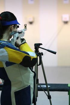 beautiful young woman aiming a pneumatic air rifle