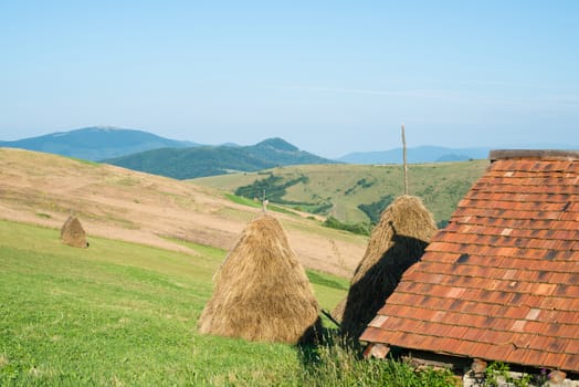Landscape in the Ukrainian Carpathian Mountains. Wooden house with orange tiled roof in the foreground,