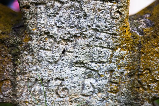 Moss-grown surface of the old stone cross with engraved Old Church Slavonic inscriptions. Kyiv, Ukraine. Close up.