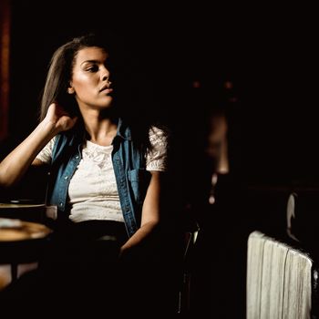 Pretty student sitting alone and thinking in a pub