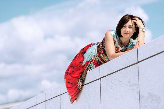 Brunette girl model in dress posing on exterior set