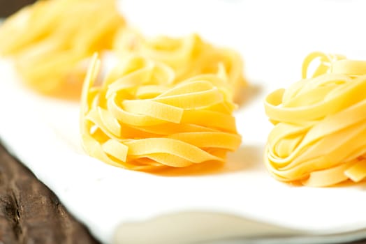 Nests of dry pasta tagliatelle on white table cloth