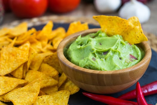 Guacamole in Wooden Bowl with Tortilla Chips and Ingredients