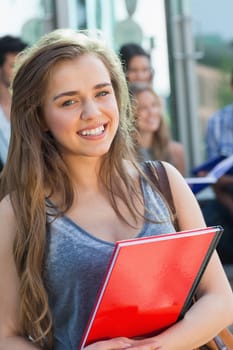 Pretty student smiling at camera outside at the university