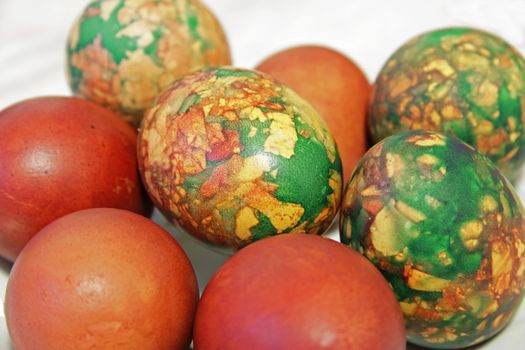 Colorful Easter eggs on white plate placed by heap