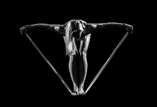 Sportswoman exercising with a resistance band on black background.