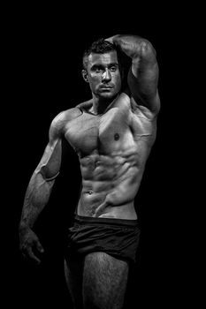 very muscular handsome athletic man on black background, naked torso, black-and-white