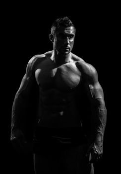 very muscular handsome athletic man on black background, naked torso, black-and-white