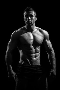 very muscular handsome athletic man on black background, naked torso, black-and-white