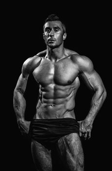 very muscular handsome athletic man on black background, naked torso, black-and-white