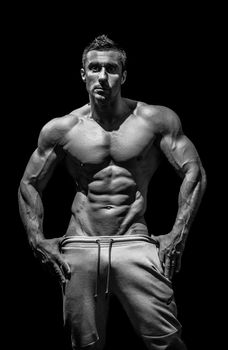 very muscular handsome athletic man on black background, naked torso, black-and-white