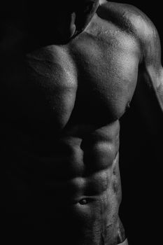 black and white studio shoot of strong athletic man on dark background