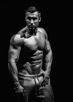 very muscular handsome athletic man on black background, naked torso, black-and-white