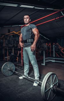 Bodybuilder preparing for deadlift of barbell 