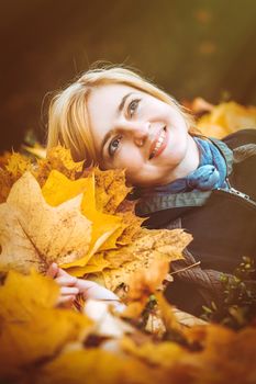 woman with autumn leaves in hand and fall yellow maple garden background