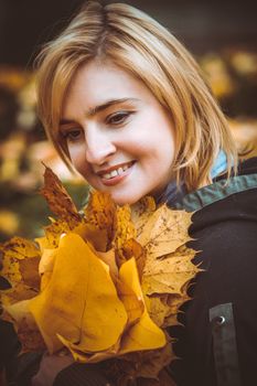 woman with autumn leaves in hand and fall yellow maple garden background