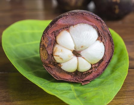 Single Mangostin and Fresh Green Leaf on Wooden Table