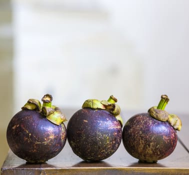 Mangostins and Fresh Green Leaf on Wooden Table