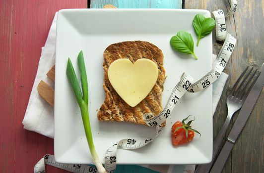 Heart shape slice of cheese on toasted whole grain bread